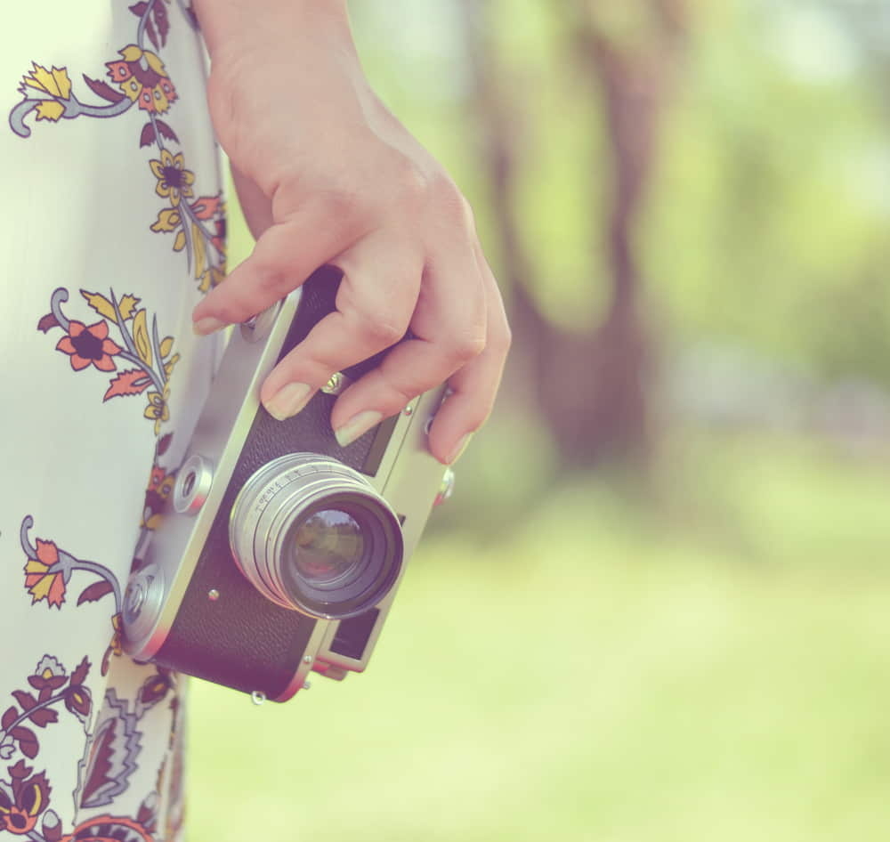 Woman hand holding retro camera close-up